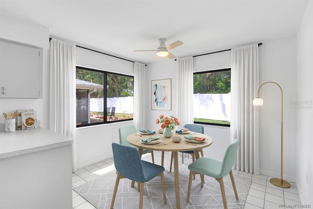 A dining area with a round table, four chairs, and windows overlooking a backyard — 4949 PLEASANT HOLLOW TRAIL UNIT 211, LAKELAND, FL