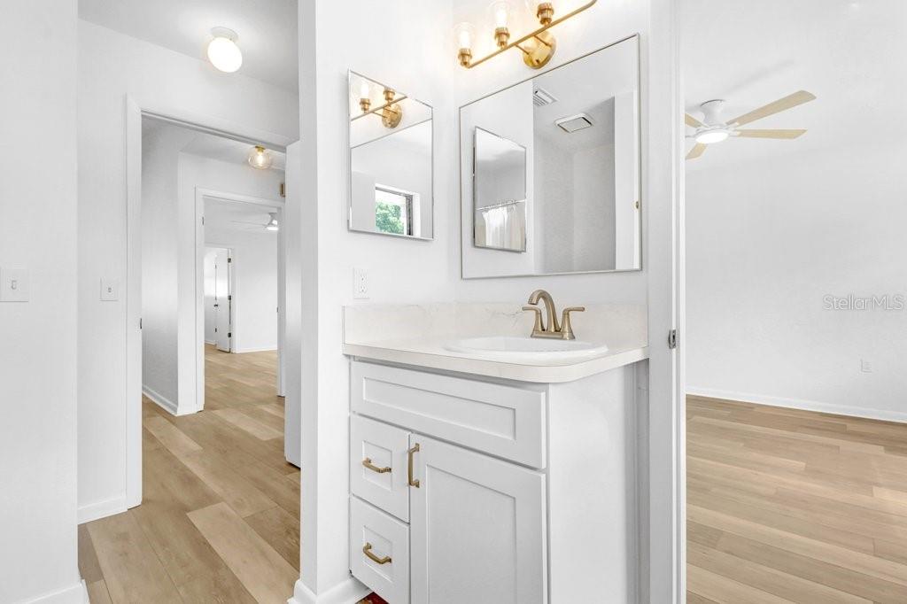 This virtually staged bedroom features white walls, light wood flooring, a ceiling fan, and furniture — 4949 PLEASANT HOLLOW TRAIL UNIT 211, LAKELAND, FL