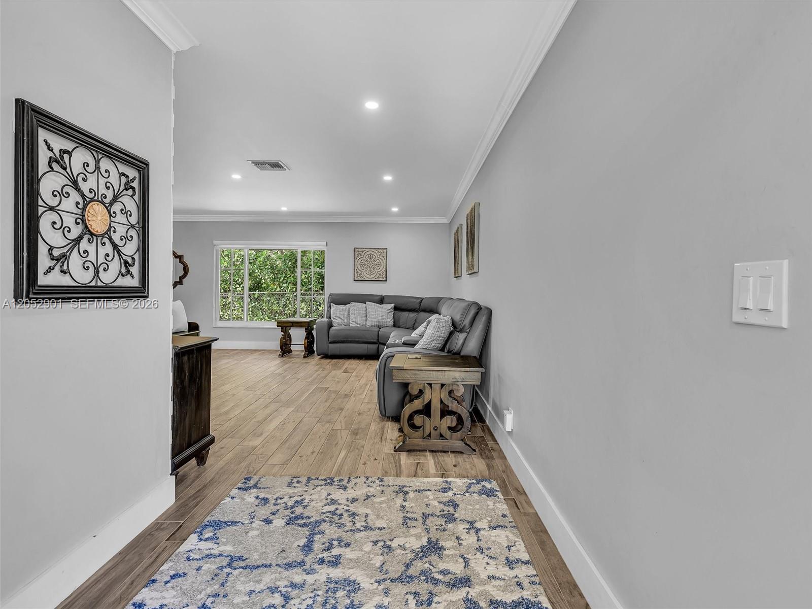 A living room features a grey sectional sofa, wood-look flooring, and a patterned area rug — 8754 SW 50th Pl, Cooper City FL 33328, COOPER CITY, FL