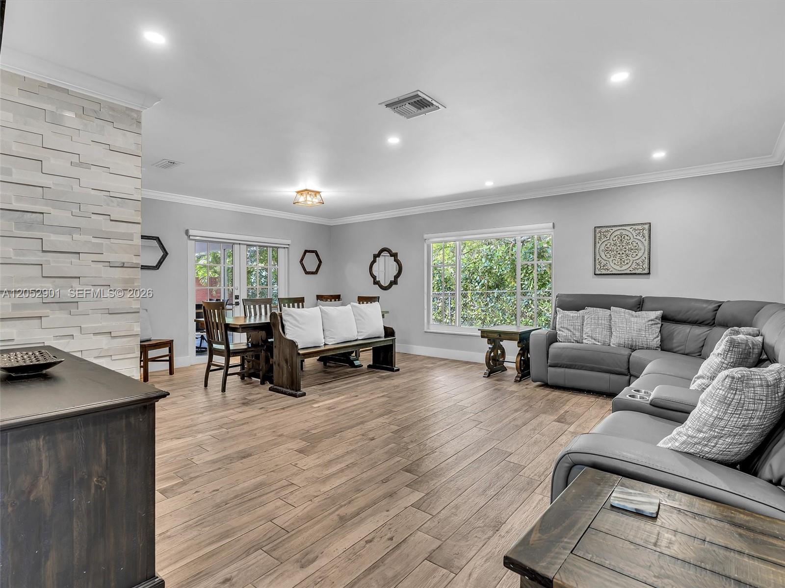 A living room features wood-look tile flooring, a stone fireplace, and a gray sectional sofa — 8754 SW 50th Pl, Cooper City FL 33328, COOPER CITY, FL