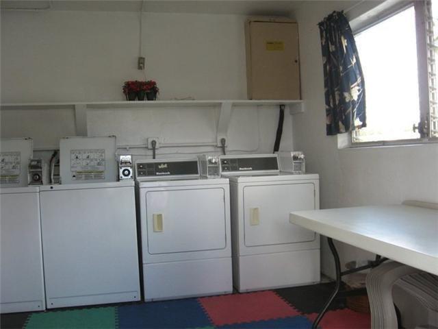 A laundry room features three white washing machines, a folding table, and a window — 301 E Mcnab Road E # 106, Pompano Beach FL 33060, POMPANO BEACH, FL