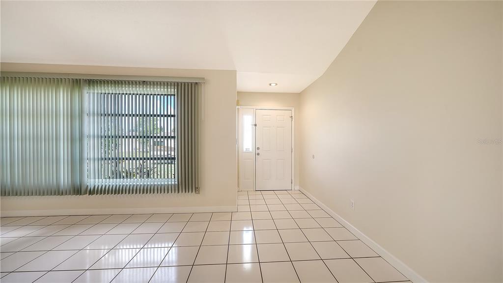 A bright entryway features white tile flooring, a front door, and a large window — 3826 BEEBER STREET, NORTH PORT, FL