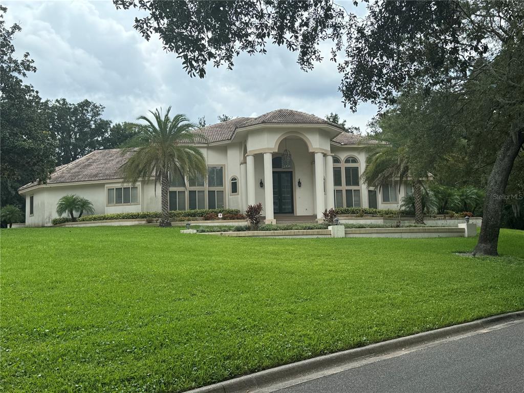 A single-story house with a columned entryway, tiled roof, and a large front lawn — 1040 SWEETWATER CLUB BOULEVARD, LONGWOOD, FL