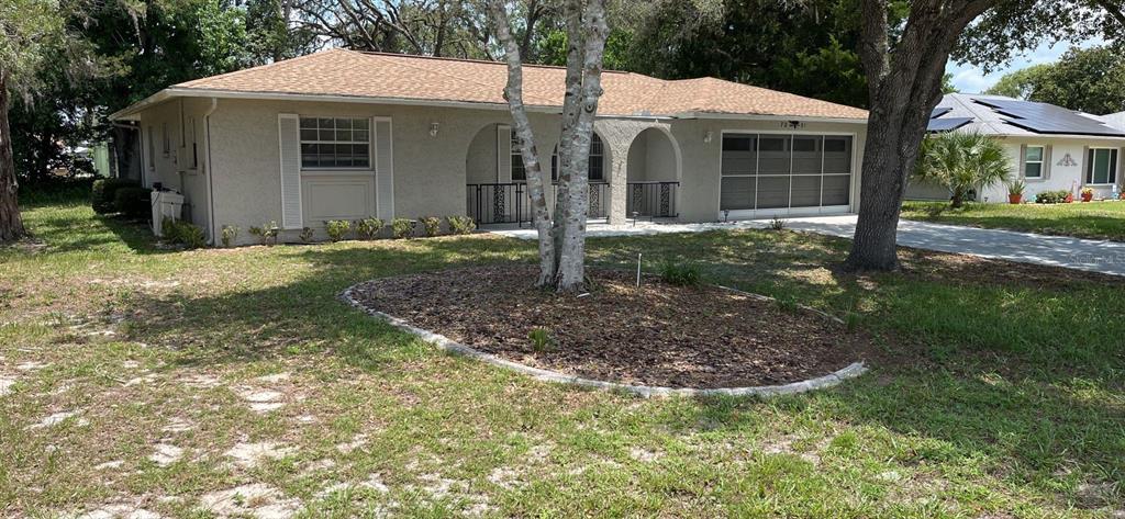 A single-story house with a beige stucco exterior, a brown shingled roof, and a garage — 7251 MCGINNES COURT, WEEKI WACHEE, FL
