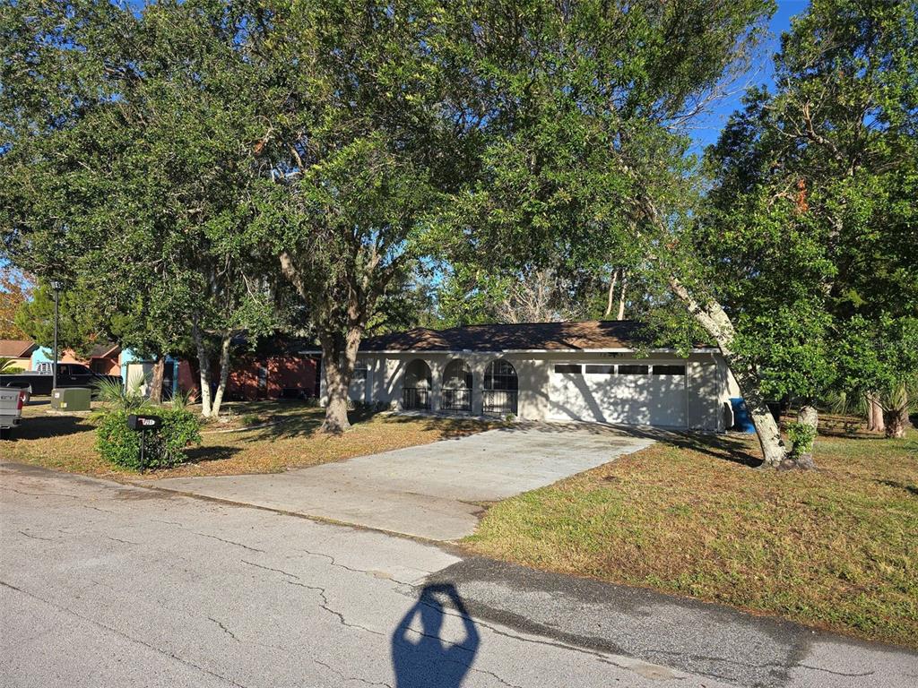 A single-story house with a white facade, arched entryway, and a two-car garage — 7251 MCGINNES COURT, WEEKI WACHEE, FL