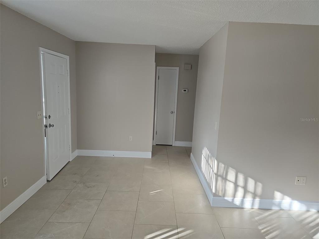 An interior view shows a room with beige tile flooring, light walls, and two doors — 7251 MCGINNES COURT, WEEKI WACHEE, FL