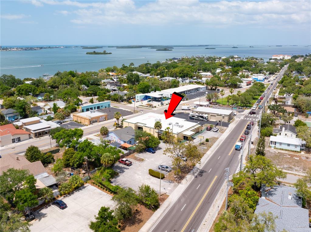 An aerial view shows a commercial building with a red arrow pointing to its roof — 1610 N MYRTLE AVENUE, CLEARWATER, FL