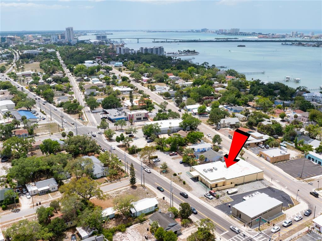 An aerial view shows a commercial building with a flat roof marked by a red arrow — 1610 N MYRTLE AVENUE, CLEARWATER, FL