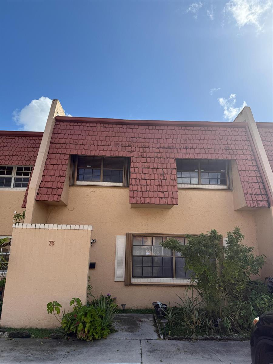 The exterior of a two-story townhouse features a mansard roof with red shingles — 76 Ann Lee Lane, Tamarac FL 33319, TAMARAC, FL