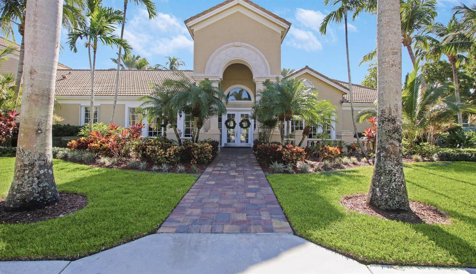 A paved walkway leads to the front entrance of a tan house with palm trees — 266 Village Boulevard # 6102, Tequesta FL 33469, TEQUESTA, FL