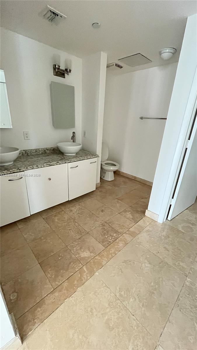 A bathroom features a double vanity with vessel sinks, white cabinets, and beige tile flooring — 350 S Miami Ave # 2302, Miami FL 33130, MIAMI, FL
