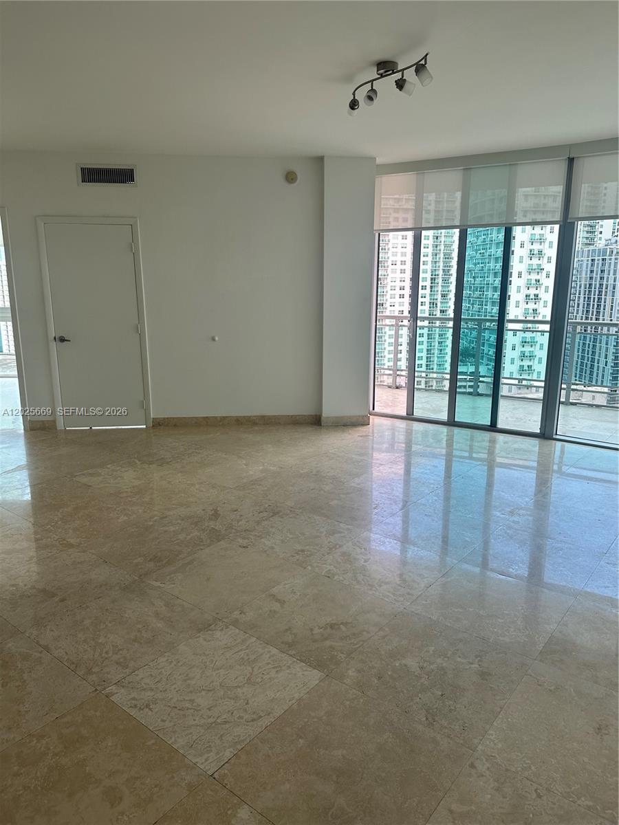 An empty room features light-colored tile flooring, a white door, and floor-to-ceiling windows — 350 S Miami Ave # 2302, Miami FL 33130, MIAMI, FL