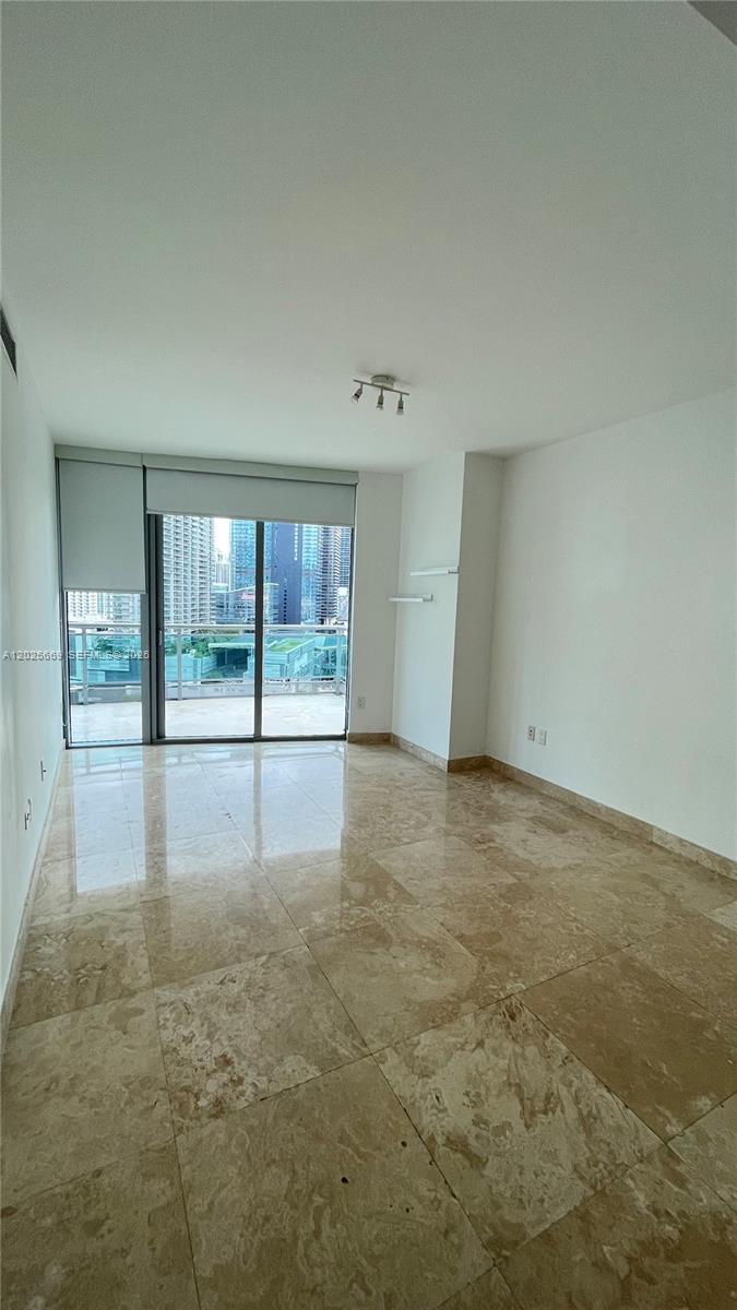 An empty room features beige marble flooring, white walls, and a sliding glass door balcony — 350 S Miami Ave # 2302, Miami FL 33130, MIAMI, FL