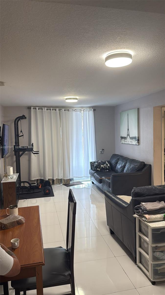 A living room features white tile floors, a black leather sofa, and a home gym — 814 NW 36th Ave # 208, Miami FL 33125, MIAMI, FL