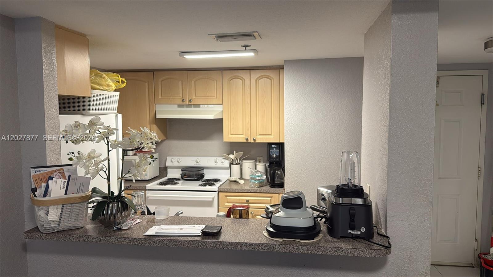 A kitchen with light wood cabinets, white appliances, and a breakfast bar counter — 814 NW 36th Ave # 208, Miami FL 33125, MIAMI, FL