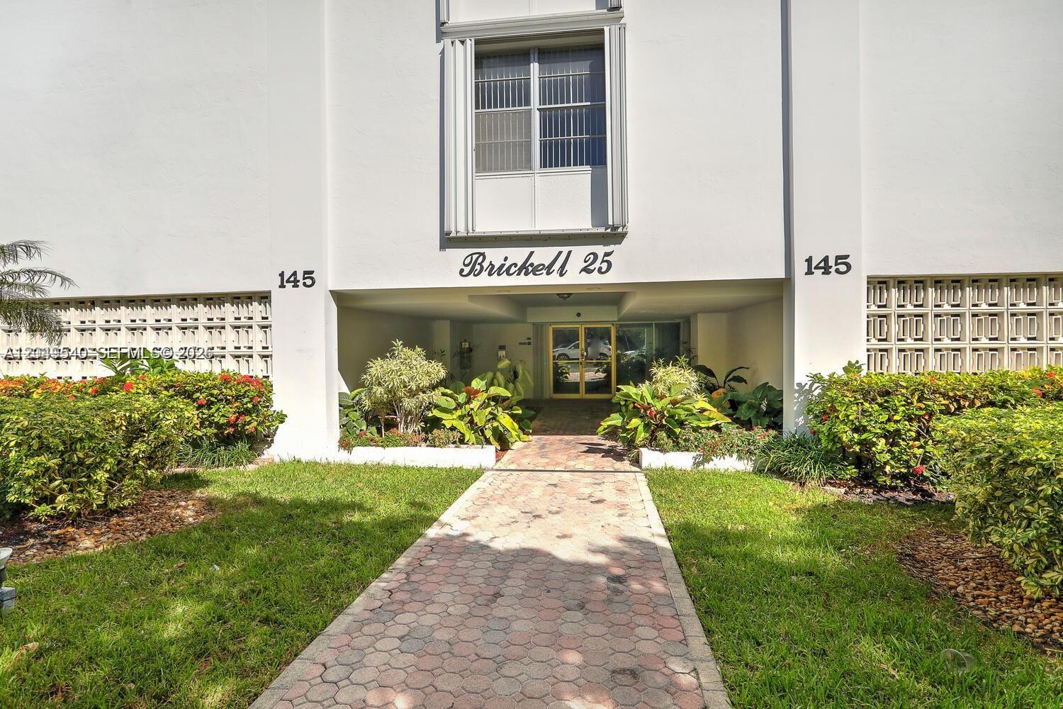 The exterior of a multi-story building features a paved walkway leading to a glass entrance — 145 SE 25th Rd # 502, Miami FL 33129, MIAMI, FL