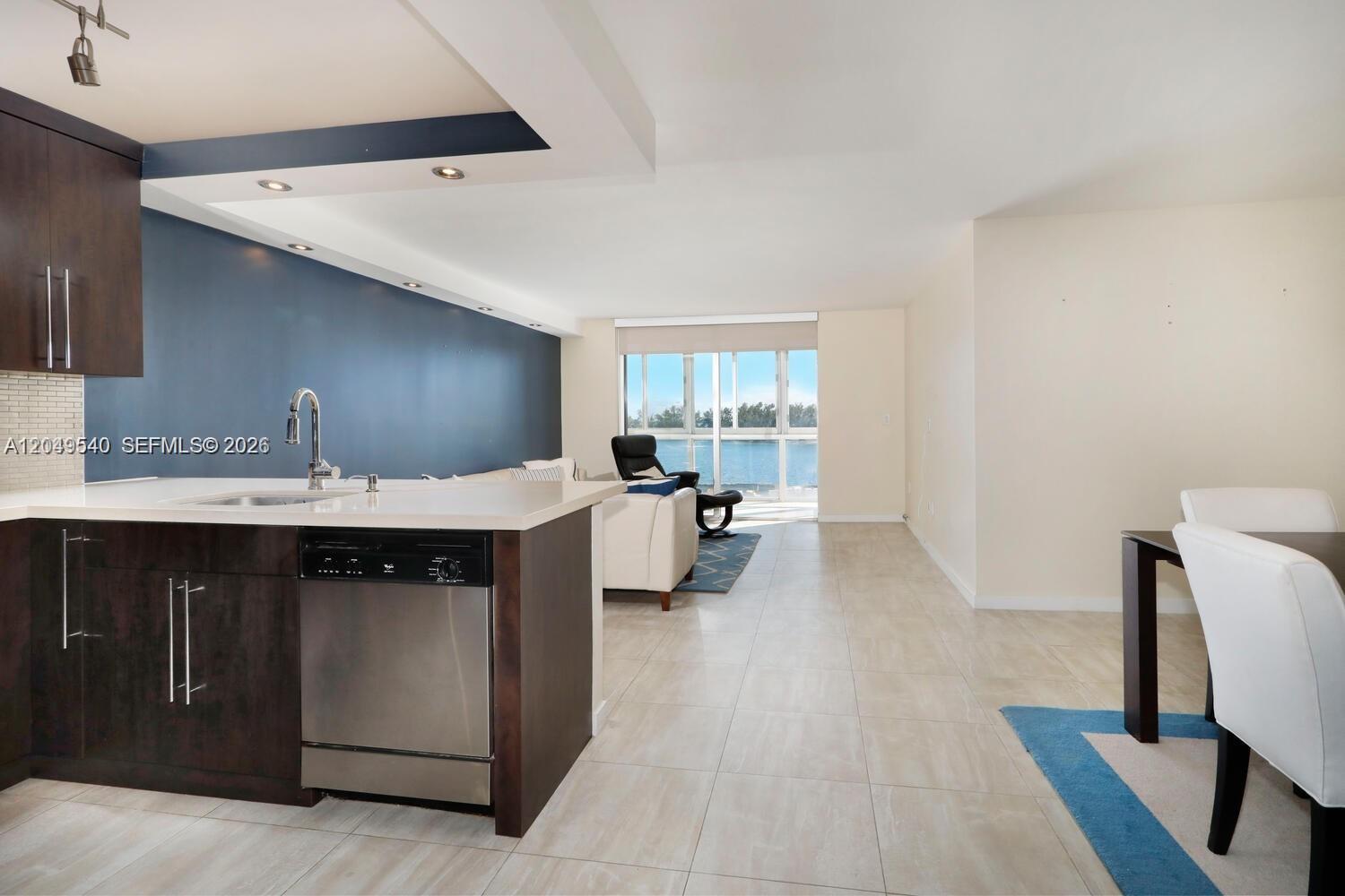 A kitchen with dark cabinets and a dishwasher overlooks a living area with water views — 145 SE 25th Rd # 502, Miami FL 33129, MIAMI, FL
