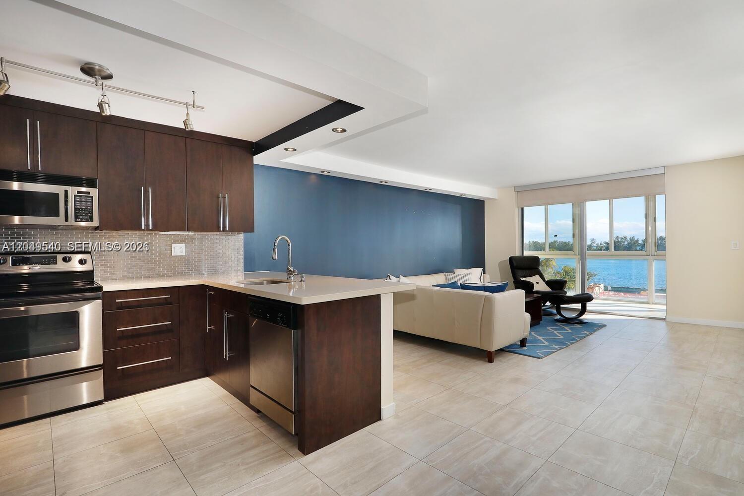 A modern kitchen with dark wood cabinets opens into a living area with water views — 145 SE 25th Rd # 502, Miami FL 33129, MIAMI, FL