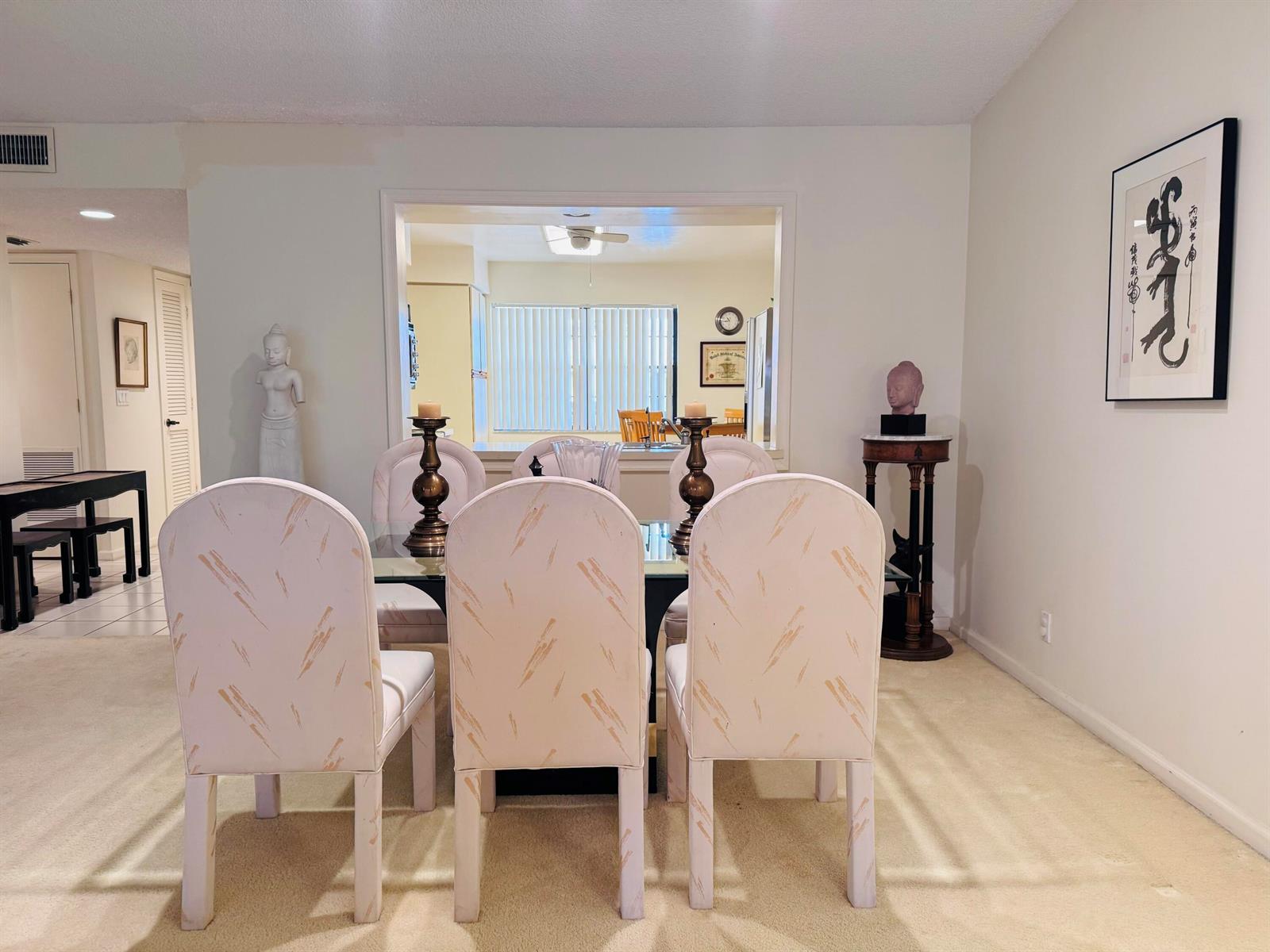 A dining room features a glass-top table with six patterned chairs and a pass-through window — 11190 Aspen Glen Drive, Boynton Beach FL 33437, BOYNTON BEACH, FL
