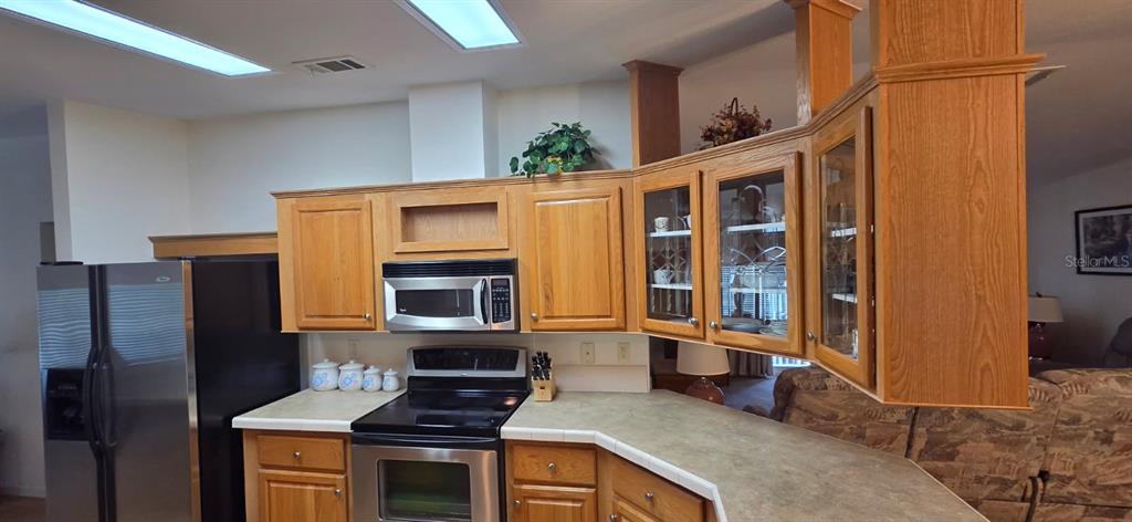 A kitchen features oak cabinets, stainless steel appliances, and a peninsula counter — 37437 GILL AVENUE, ZEPHYRHILLS, FL