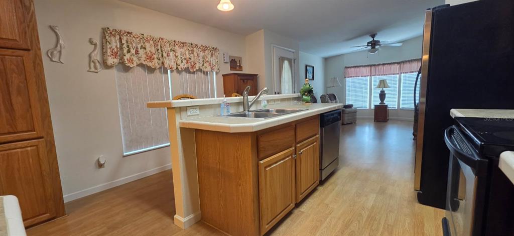 A kitchen with wood cabinets, a tiled island, and a stainless steel dishwasher — 37437 GILL AVENUE, ZEPHYRHILLS, FL