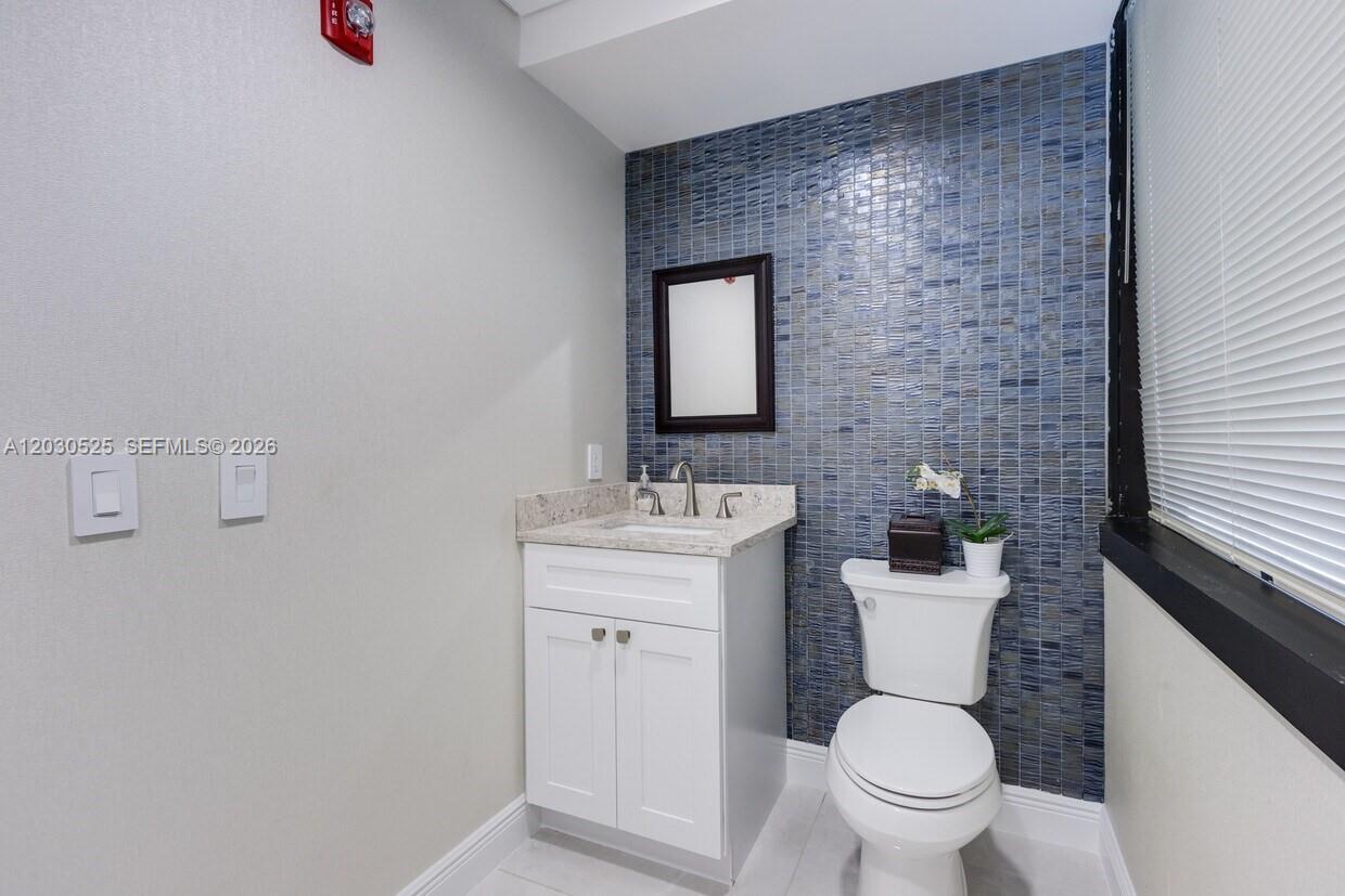 A bathroom features a white vanity, a toilet, and a blue tiled accent wall — FORT LAUDERDALE, FL
