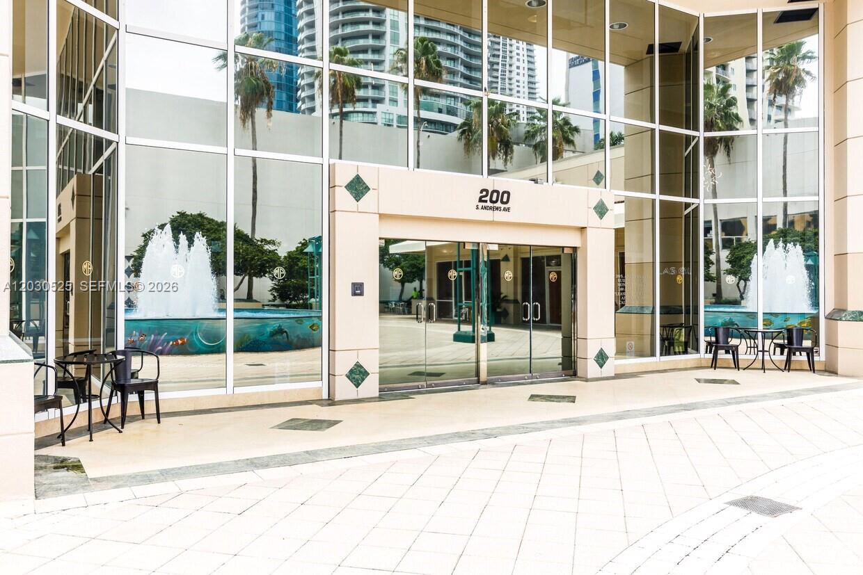 The exterior entrance of a building features glass doors, large windows, and a fountain — FORT LAUDERDALE, FL