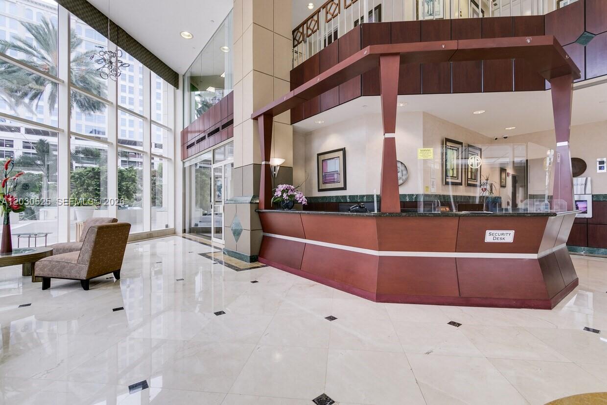A lobby features a large wooden security desk, marble floors, and floor-to-ceiling windows — FORT LAUDERDALE, FL