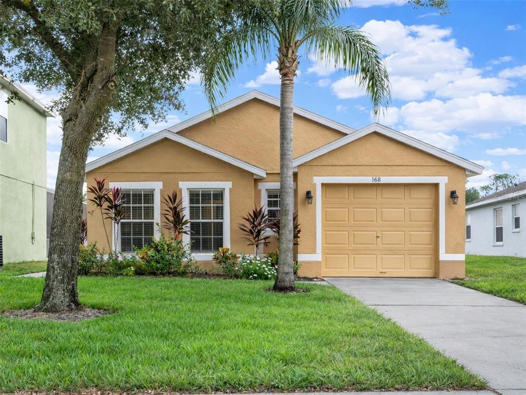 A single-story tan house with a one-car garage and a palm tree in the yard — 188 RIDGEMONT COURT, DAVENPORT, FL