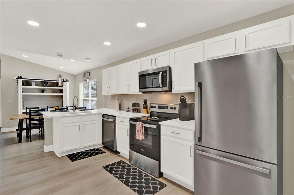 A kitchen features white cabinets, stainless steel appliances, and light wood-look flooring — 188 RIDGEMONT COURT, DAVENPORT, FL
