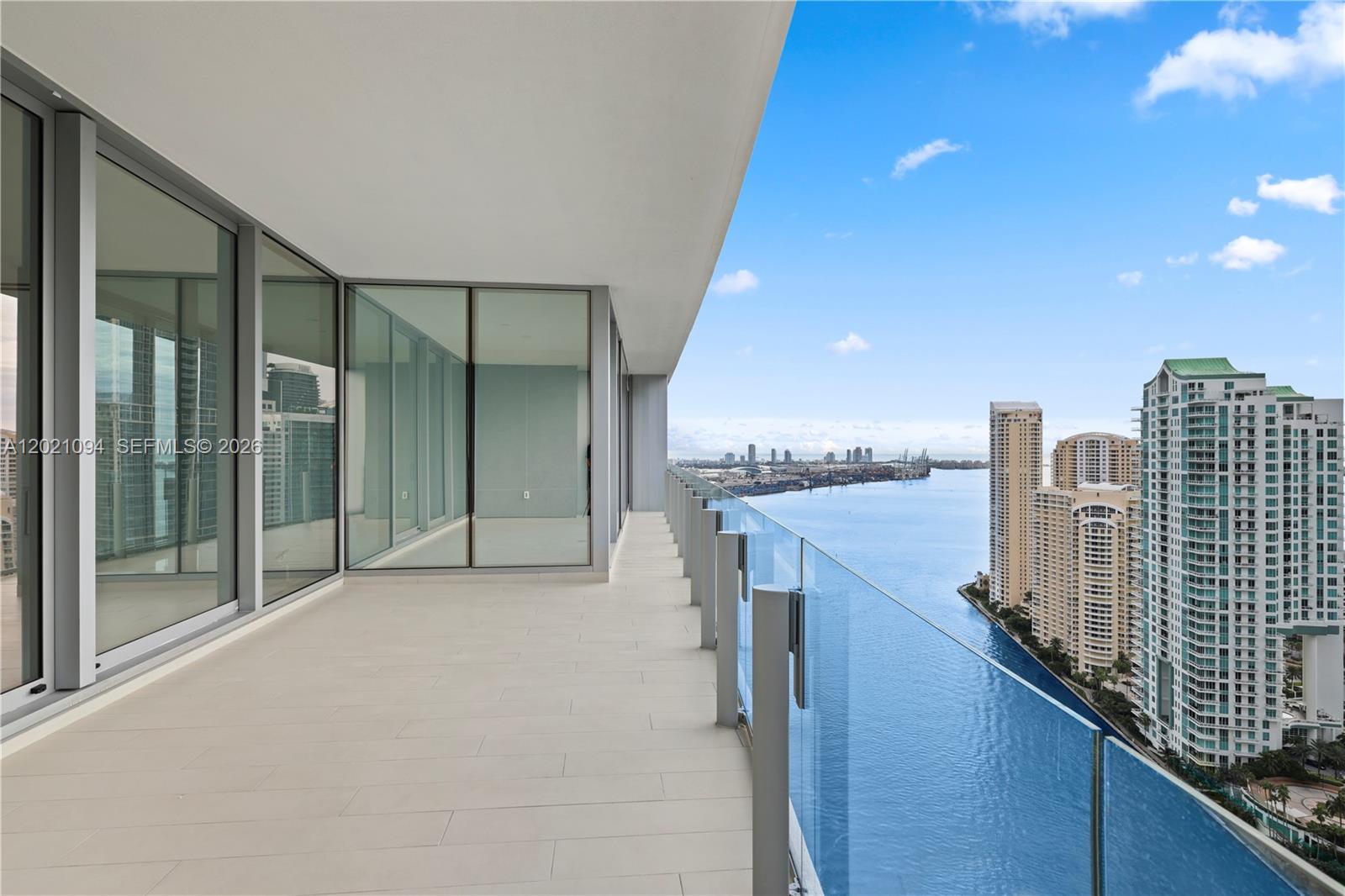 A high-rise balcony with glass railings overlooks a bay and city skyline — 300 Biscayne Blvd Way # 3404C, Miami FL 33131, MIAMI, FL