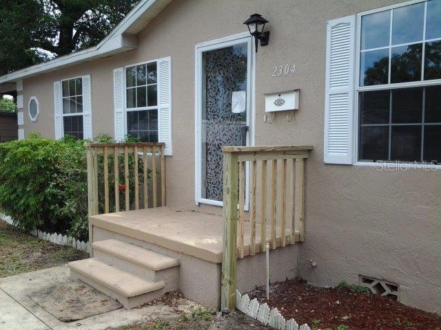 The exterior of a house features a concrete porch with wooden railings and white shutters — 2304 KINGSTON STREET S, ST PETERSBURG, FL