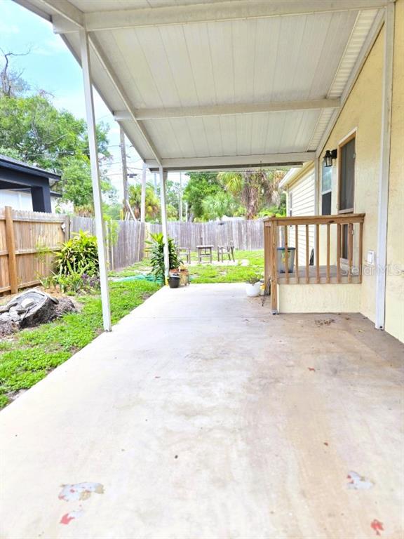 A covered concrete patio leads to a small wooden deck and a fenced backyard — 2304 KINGSTON STREET S, ST PETERSBURG, FL