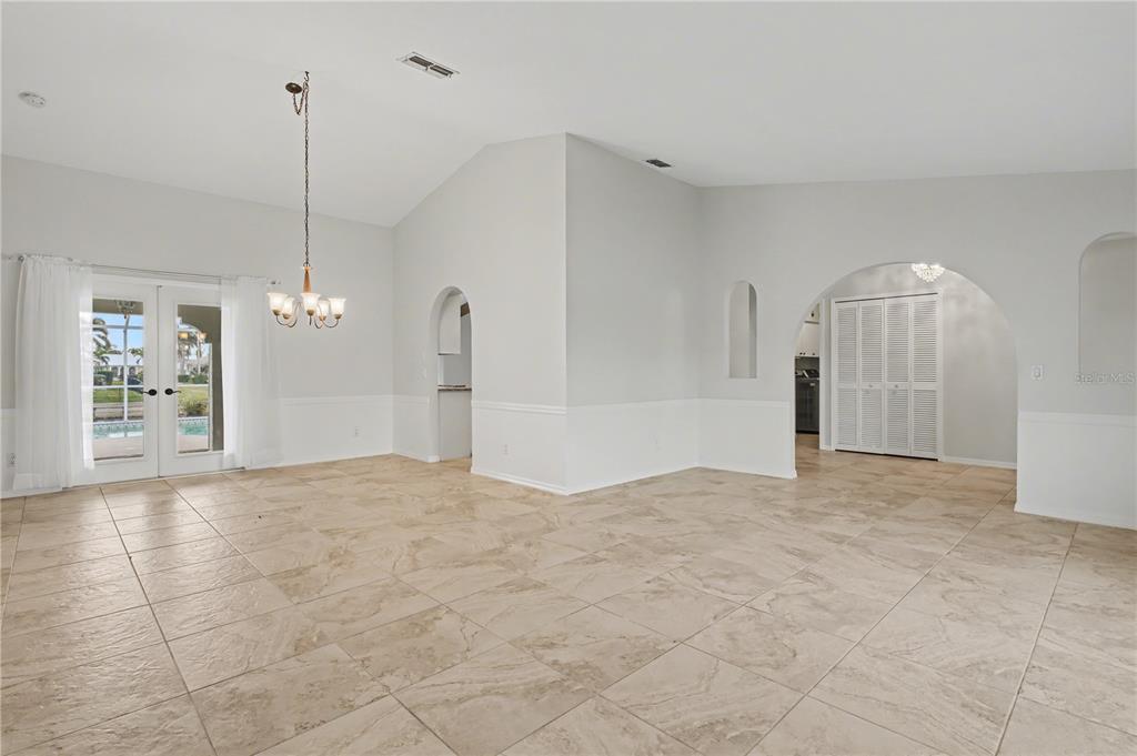 An open-concept dining area features vaulted ceilings, tile flooring, and arched doorways leading to other rooms — 1119 VIA FORMIA, PUNTA GORDA, FL