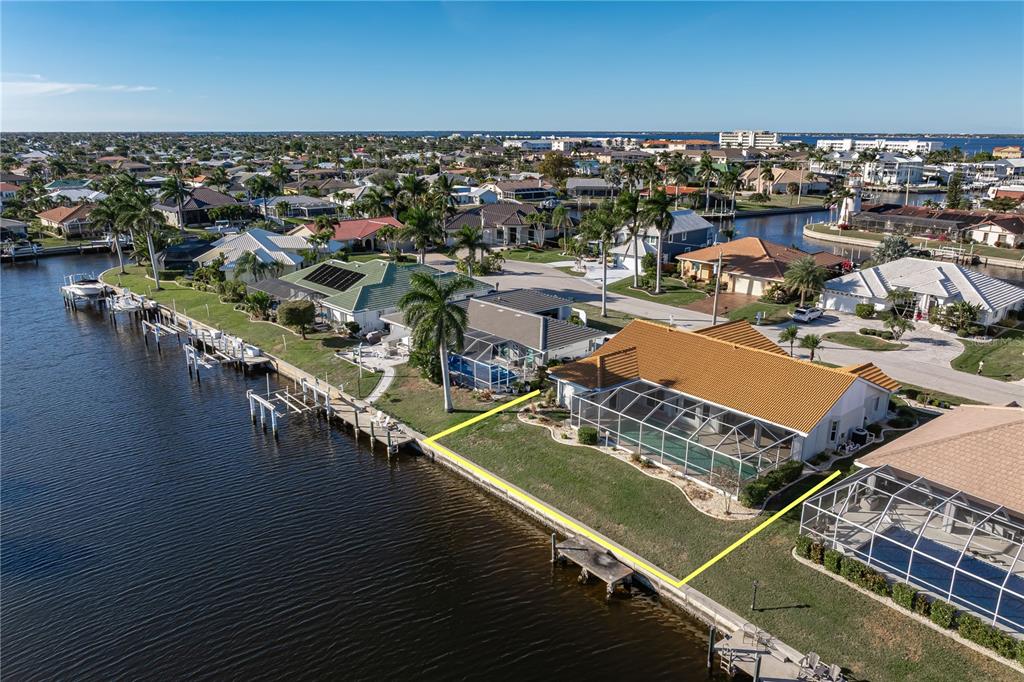 An aerial view shows a waterfront house with a pool cage and a private dock — 1119 VIA FORMIA, PUNTA GORDA, FL