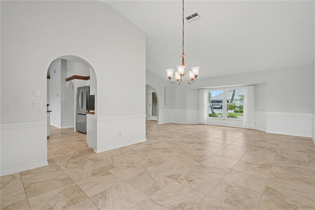 A bright, open-concept dining area features beige tile flooring, white walls, and a chandelier — 1119 VIA FORMIA, PUNTA GORDA, FL