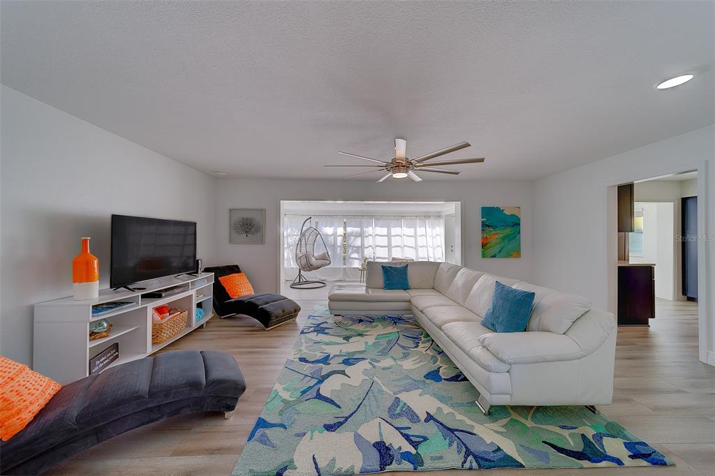 A living room features a white sectional sofa, a patterned area rug, and a television console — 2109 BAYSHORE DRIVE, BELLEAIR BEACH, FL