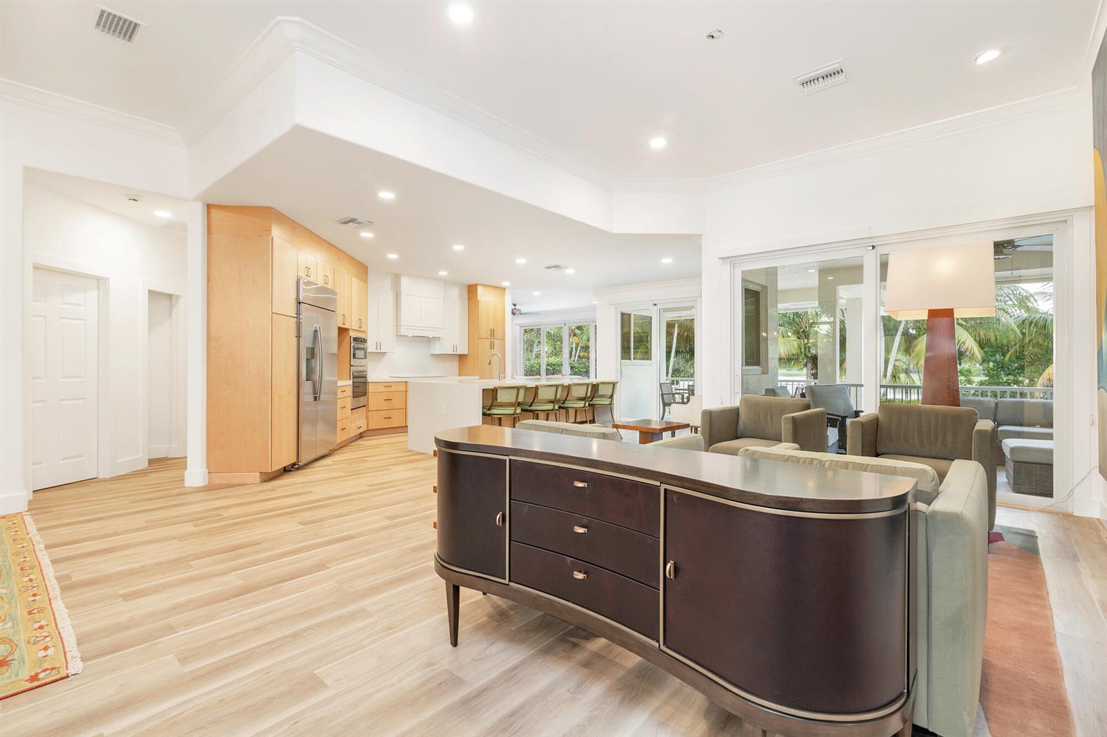 A living room with a dark wood console table, light wood floors, and an open kitchen — 3317 Embassy Drive, West Palm Beach FL 33401, WEST PALM BEACH, FL