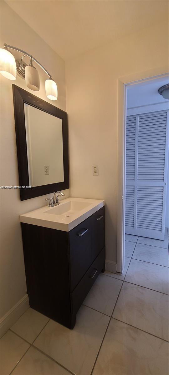 A bathroom features a dark vanity with a white sink, a mirror, and light fixtures — 1540 NE 191st St # 207, Miami FL 33179, MIAMI, FL