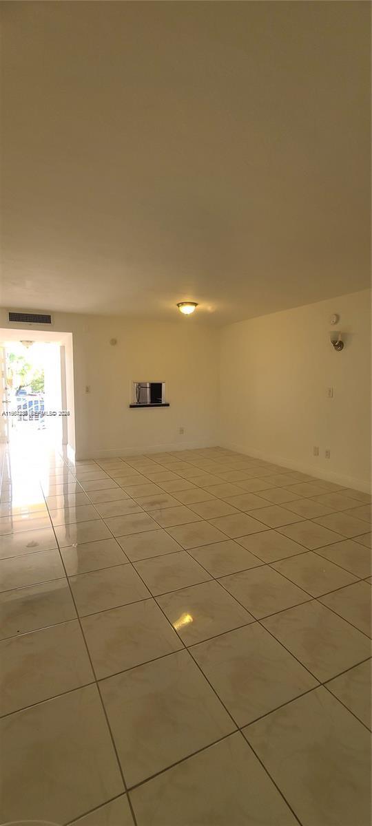 An empty room with white walls, beige tile flooring, and a doorway leading outside — 1540 NE 191st St # 207, Miami FL 33179, MIAMI, FL