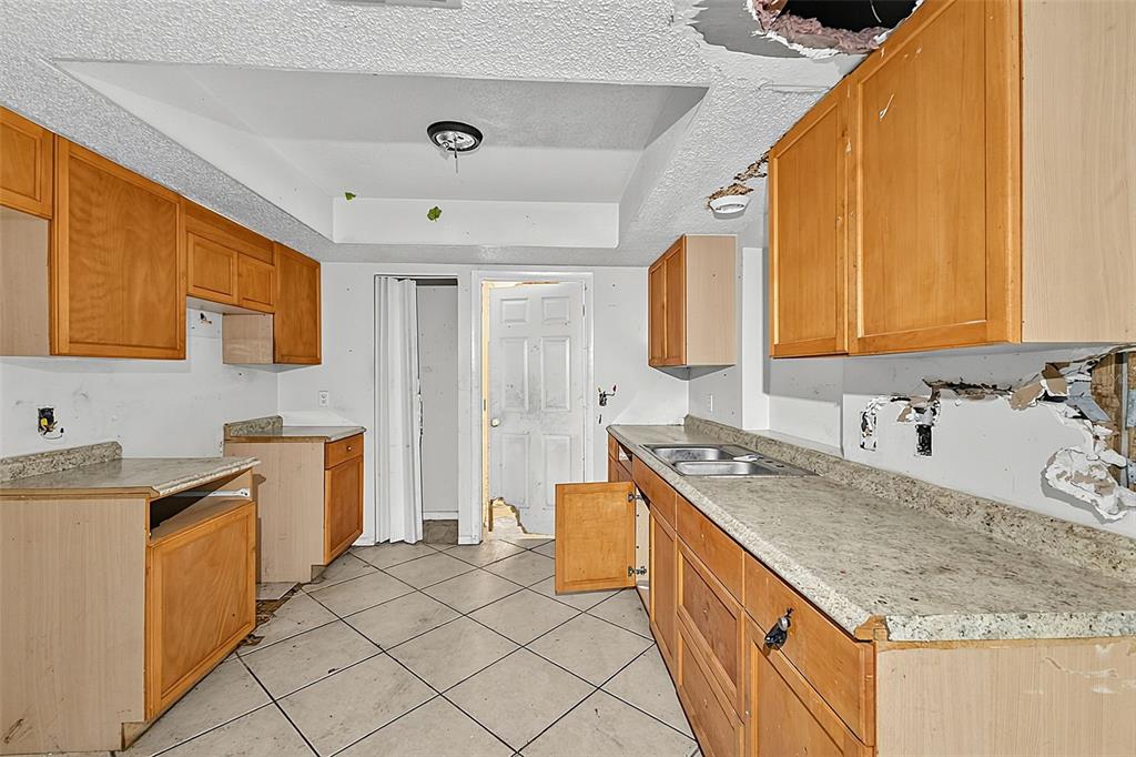 An open-concept kitchen and living area with tiled floors, wooden cabinets, and a mirrored wall — 4830 COCO PALM DRIVE, SEBRING, FL