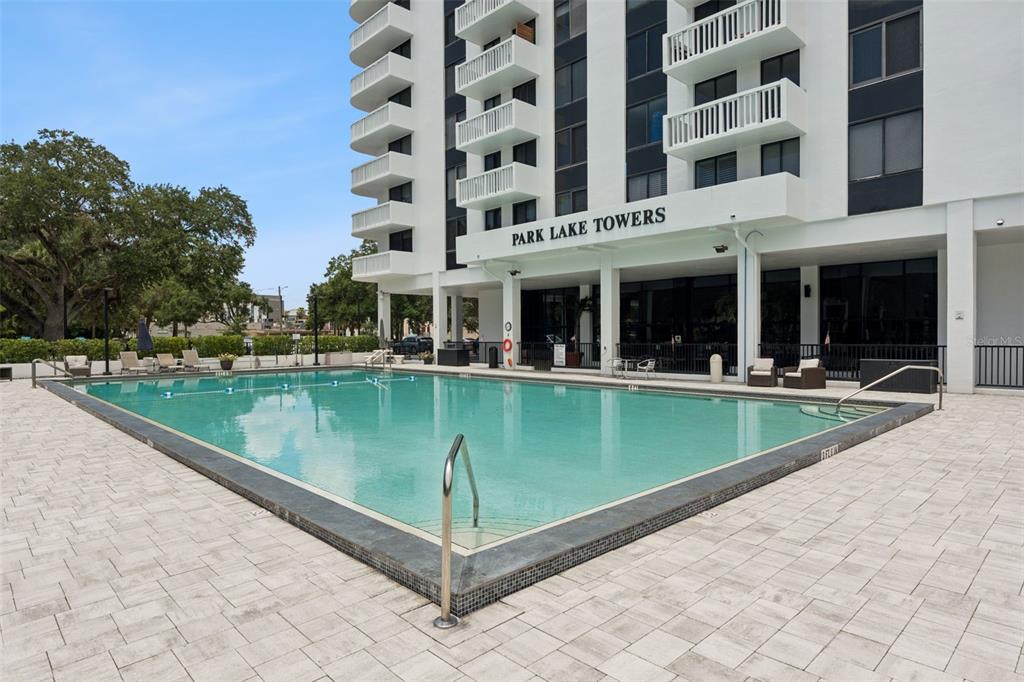 A swimming pool sits on a paved patio in front of a white high-rise building — 400 E COLONIAL DRIVE UNIT 608, ORLANDO, FL