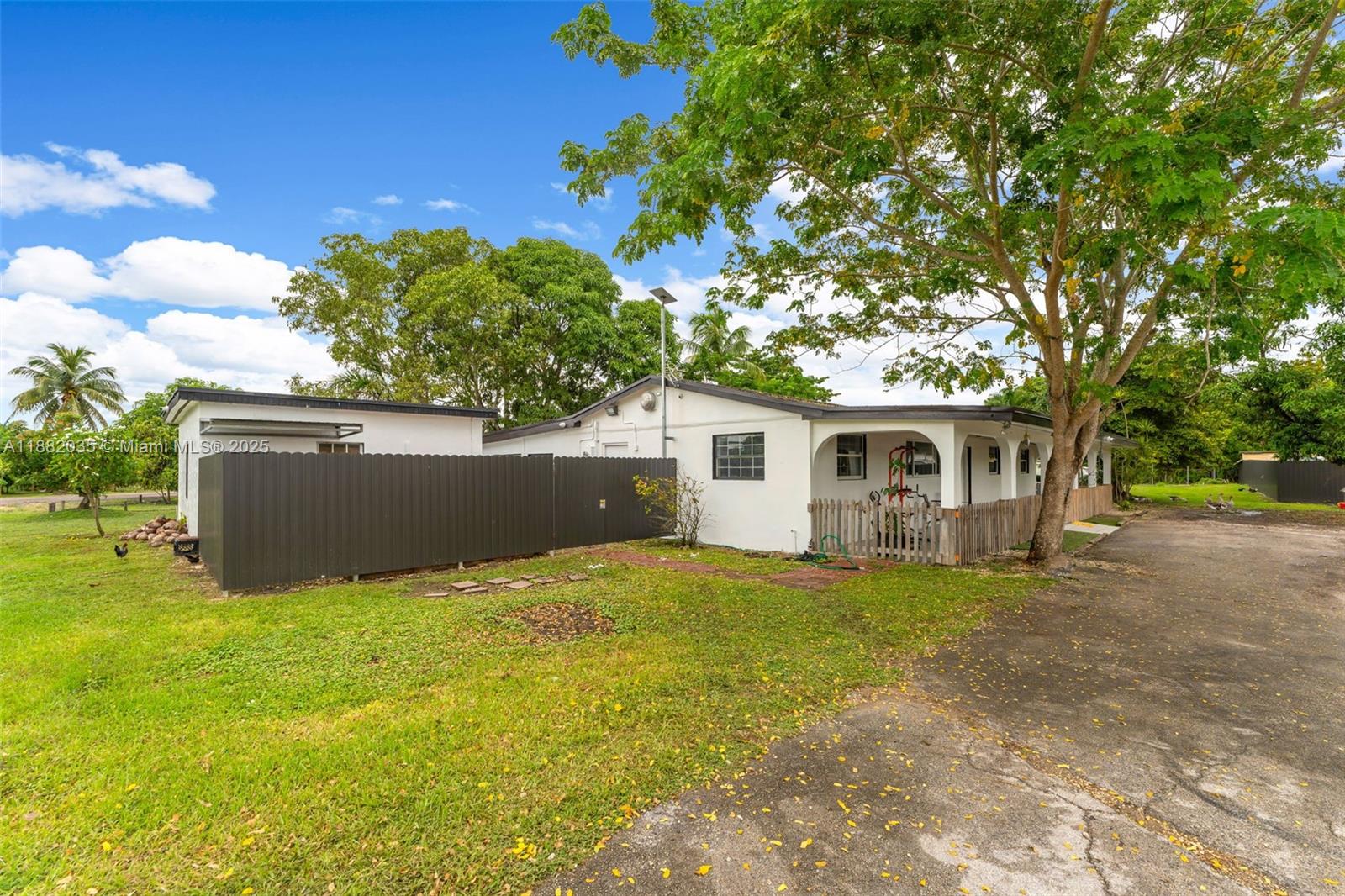 A white single-story house with a fenced yard and a large tree in front — 12750 SW 197th Ave, Miami FL 33196, MIAMI, FL