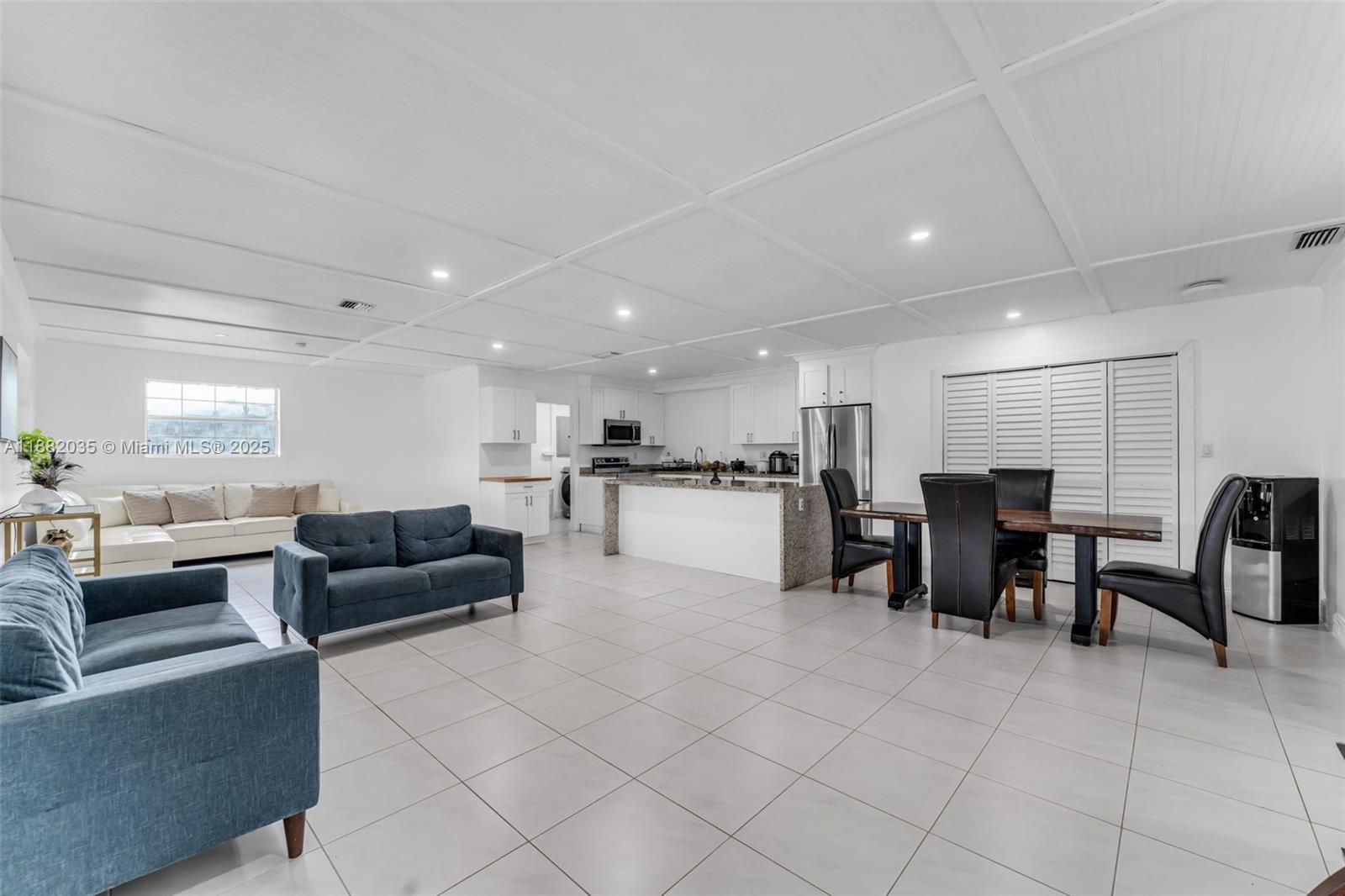 An open-concept living and dining area features white tile floors, a coffered ceiling, and a kitchen — 12750 SW 197th Ave, Miami FL 33196, MIAMI, FL