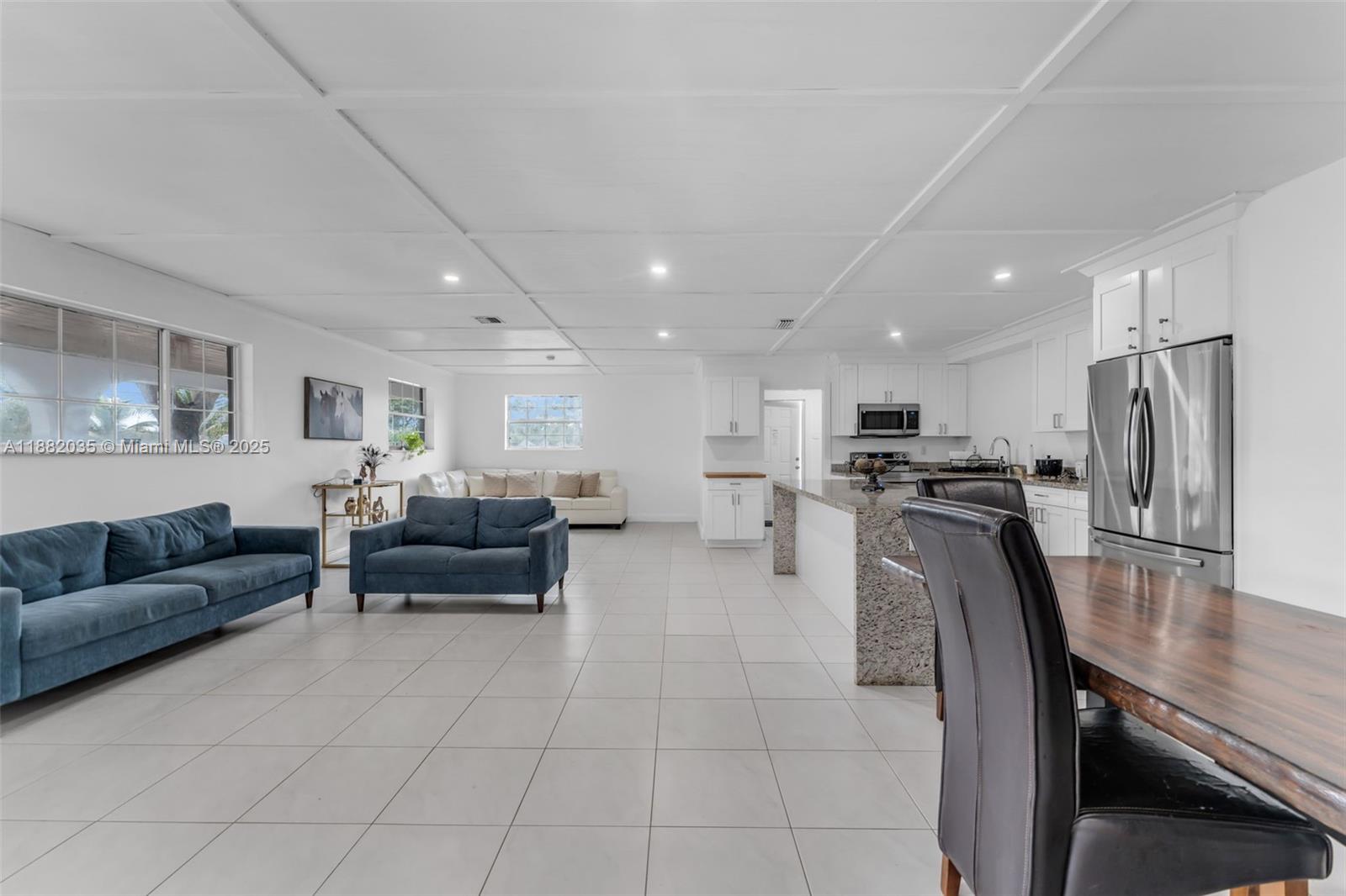 An open-concept living area features a kitchen with granite countertops and a tiled floor — 12750 SW 197th Ave, Miami FL 33196, MIAMI, FL