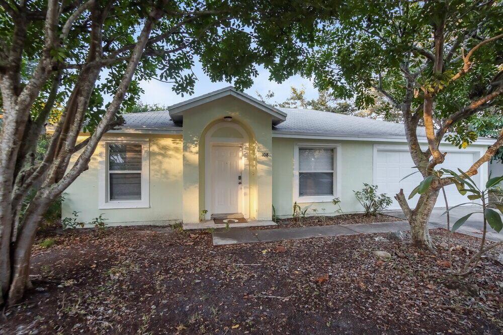 A light green single-story house with a white front door and an attached garage — SEBASTIAN, FL