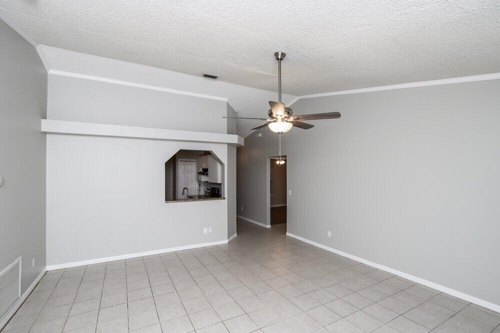A living room with gray walls, tile flooring, a ceiling fan, and a kitchen pass-through window — SEBASTIAN, FL