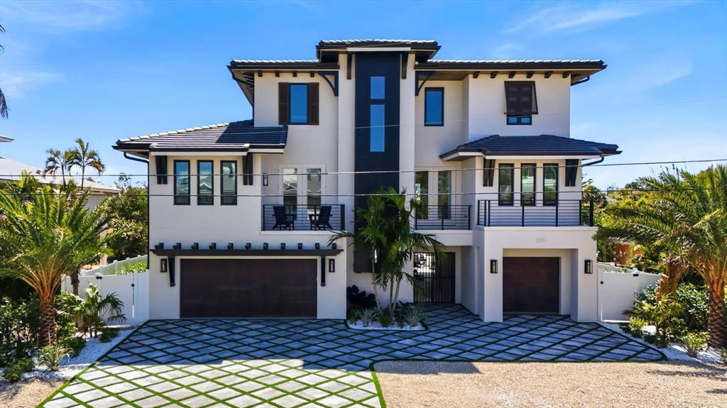 A modern three-story house with a white exterior, dark trim, and a patterned paver driveway — 319 TARPON STREET, ANNA MARIA, FL