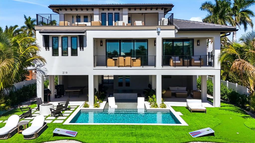 A multi-story house with a pool, patio furniture, and a putting green in the backyard — 319 TARPON STREET, ANNA MARIA, FL