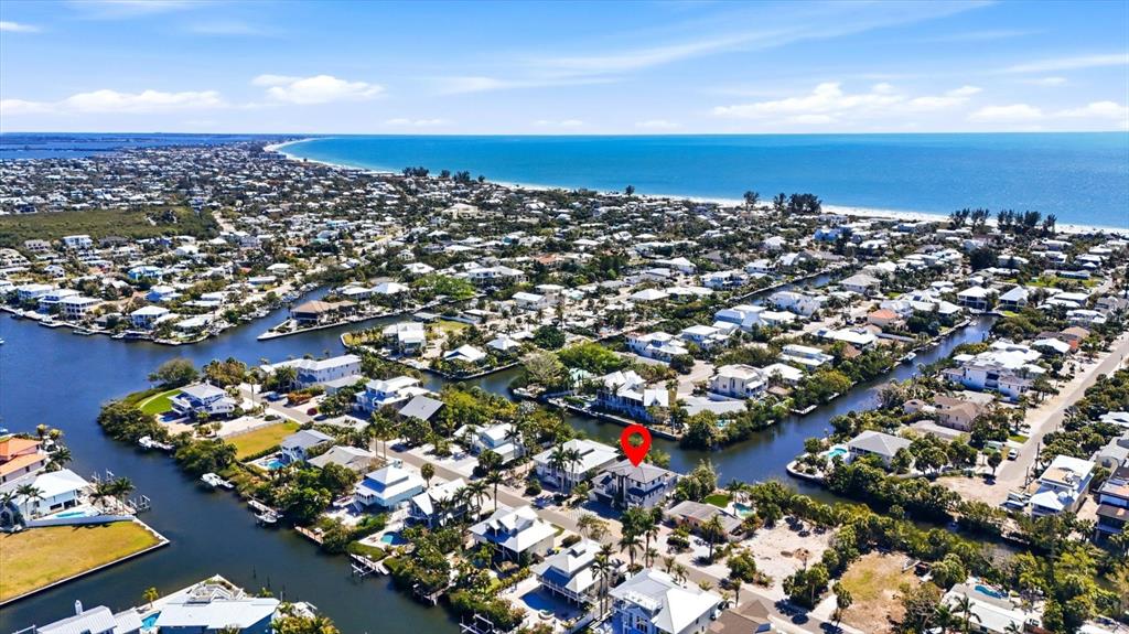 An aerial view shows a coastal neighborhood with houses situated along interconnected canals near the ocean — 319 TARPON STREET, ANNA MARIA, FL